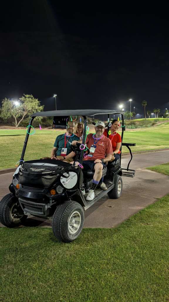 The Par-tee animals golf team sitting in a golf cart on the par 3 course in Tempe. The golf cart is decorated with an Evergreen logo and glow stick necklaces